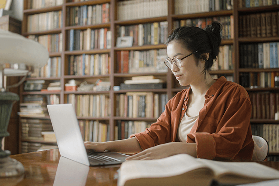 A young woman working on laptop while sitting in a library
